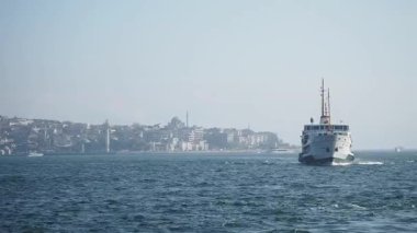 Bir tekne hareketli bir sahil kenti yakınlarındaki berrak sularda sorunsuzca seyahat eder..