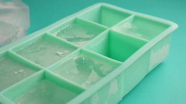 Buz küpleri parlak mavi bir yüzey üzerinde yeşil bir tepside şekilleniyor..
