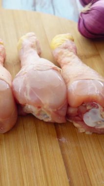 İki çiğ tavuk budu ahşap bir tahtada soğanlı oturur..