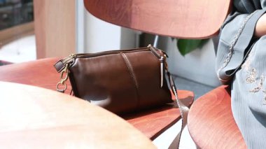 Modern bir kafede bir sandalyeye güzel hazırlanmış kahverengi bir çanta..