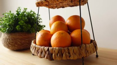 Parlak portakallar ahşap bir masada dekoratif bir sepete yerleştirilmiş..