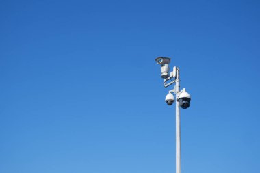 Gözetleme kameraları parlak mavi gökyüzünün altındaki uzun bir direğe yerleştirilmiştir..
