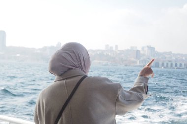 Açık renk ceketli kadın, İstanbul 'daki uzak şehir manzarasına doğru hareket ediyor.