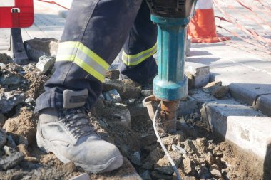 İşçi kentsel onarımlar sırasında beton kırmak için matkap kullanıyor.