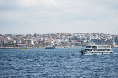 Feribot, yakınlarda canlı bir şehir manzarası ile su üzerinde seyahat eder..