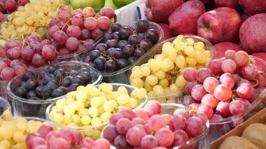 Çeşitli üzüm ve elmalar içeren canlı meyveler müşteri seçimini bekliyor.