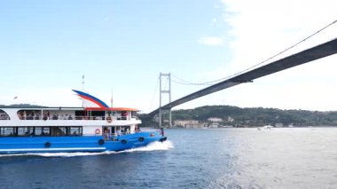 İstanbul 'da modern bir köprünün altından bir tekne geçiyor.