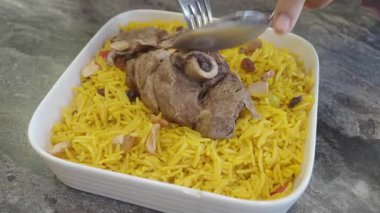 Yumuşak kuzu dilimleniyor ve aromatik safran pirinç ve fındık ile servis ediliyor..