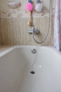 Su, renkli banyo aksesuarları eşliğinde temiz bir küvete akar..