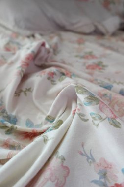 Yatak örtülerindeki narin çiçek desenleri sıcak ve davetkar bir alan yaratır..