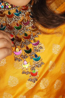 Parlak, şenlikli bir kıyafet giyerken karmaşık takılara hayranlık duyan biri..