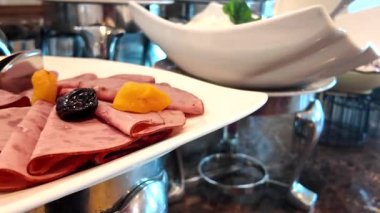 Bir büfede zarif bir şekilde sergilenen jambon ve kurutulmuş meyve tabağı.