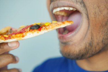 Rahatlamış bir atmosferde bir insan lezzetli bir pizzadan bir ısırık alır..