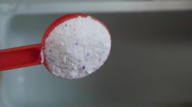 Çamaşırları yıkamak için bir kepçeye belirli miktarda deterjan dökmek..