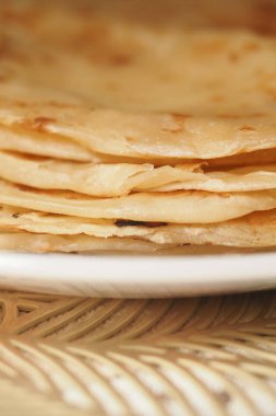 Yumuşak, taze düz ekmekler bir tabakta güzelce istiflenmeye hazır..