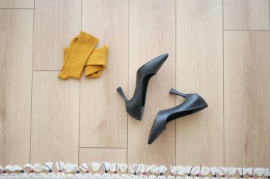 Sarı çoraplarla eşleştirilmiş siyah topuklar yerde şık bir kontrastlama yaratır..