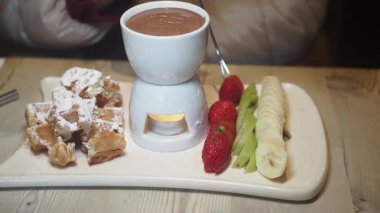 Meyve ve waffle ile servis edilen lezzetli çikolata fondüsünün tadını çıkarın..