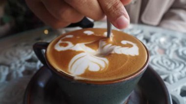 Bir barista, kahvenin üstüne karışık latte sanatı dizayn eder..