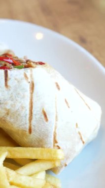 Patates kızartmasının yanında taze malzemelerle dolu lezzetli bir dürümün tadını çıkarıyorum..