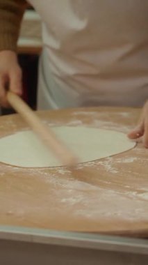 Yetenekli bir fırıncı lezzetli yemekler için un kaplı bir yüzeye hamur döker..