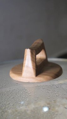 Yüzeyinde buhar olan bir tencere kapağının ahşap sapının yakın görüntüsü..