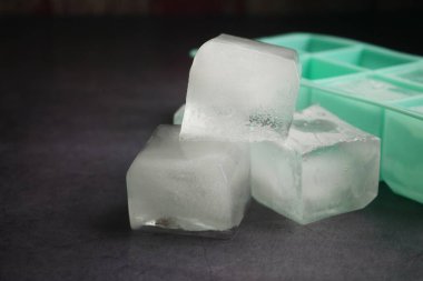 Temiz buz küpleri buz kalıbının yanında oturur, pürüzsüz kenarlarını sergilerler..