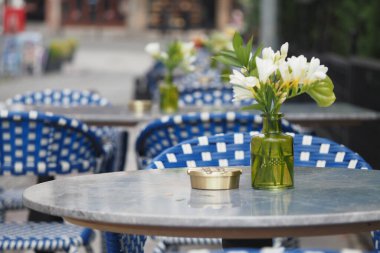 Çiçeklerle süslenmiş masalar ve bir kül tablası ziyaretçileri rahatlamaları için davet ediyor..