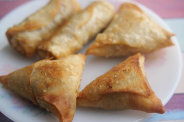 Bir tabakta gevrek samosalar, altın rengi ve deseni sergiliyor..