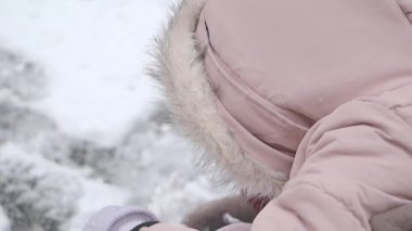 Kışlık giysiler içinde karlı havanın tadını çıkaran küçük bir çocuk..