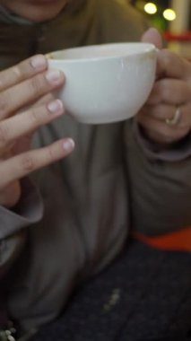 Bir kafe ortamında dinlenirken bir bardak sıcak içecek içen kişi.