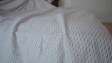 Basit bir odada yatak yapan kişi..