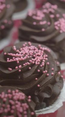 Zengin, koyu çikolatalı keklerin üzerine pembe şekerlemeler serpiştir..