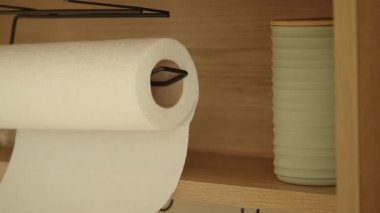 Kağıt havlu rulosu mutfak rafında seramik bir konteynırın yanında duruyor..