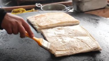 Bir aşçı, canlı bir pazar ortamında sıcak bir ızgaranın üzerinde düz ekmek hazırlar..