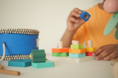 Bir çocuk renkli ahşap şekillerle meşgul olur, eğlenceli öğrenmeye odaklanır..