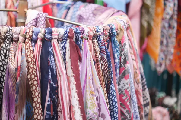 Kalabalık bir pazarda sayısız canlı eşarp satılık..