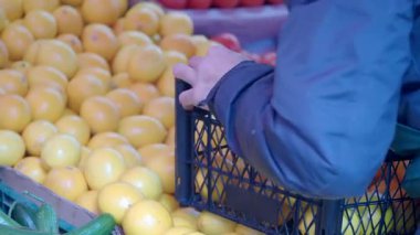 Bir insan pazardaki bir kasadan parlak sarı limon seçiyor..