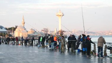 Balıkçılar şafak vakti suya dökülen bir iskelede kuyruk oluşturuyorlar..