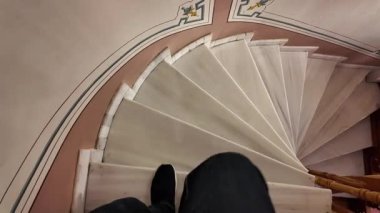 Bir insan mermer basamaklı güzel dizayn edilmiş spiral bir merdivenden iner..