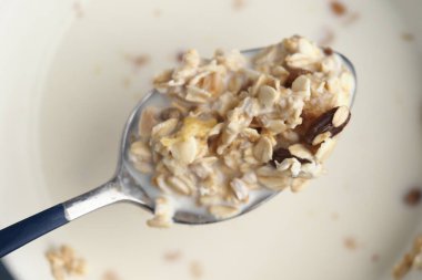 Sütlü yulaf ezmesi ve çeşitli malzemeler mutfak ortamında kaşığın üzerinde duruyor..