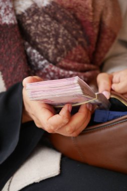 Tek başına oturuyor, elinde büyük bir kağıt ya da belge koleksiyonu var..