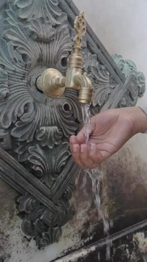 Bir el, güzel tasarlanmış musluktan ferahlatıcı su yakalıyor..