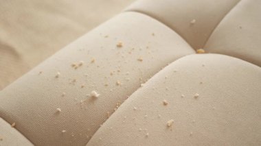 Aydınlık kumaş koltukta kırıntılar ve enkaz parçaları. 