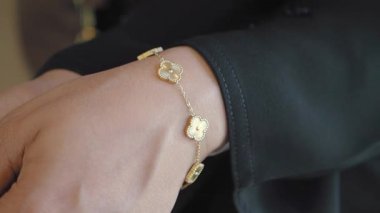 Şık bir toplantıda bileğindeki altın bir bileziğin yakın çekimi..