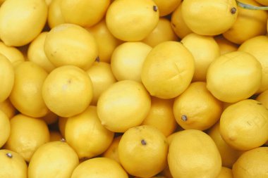 Sarı limonlar üst üste yığılmış, parlak ve sulu görünümlerini sergiliyorlar..