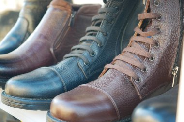 Ahşap bir tezgahta sergilenen farklı deri çizmeler..