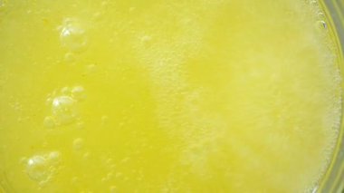 Canlı sarı bir içecek bardakta karbonat ile köpürüyor..