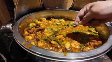 Aşçı taze malzemelerle aromalı karides körisi karıştırıyor..