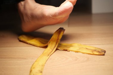 Bir evin ahşap zemininde muz kabuğunun üzerinde bir ayak uçar..