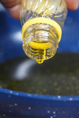 Yemek hazırlığı için mavi bir kaseye yağ dökülüyor..